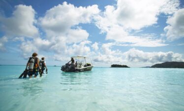 Guests walking towards a boat in clear waters at Paradise Sun