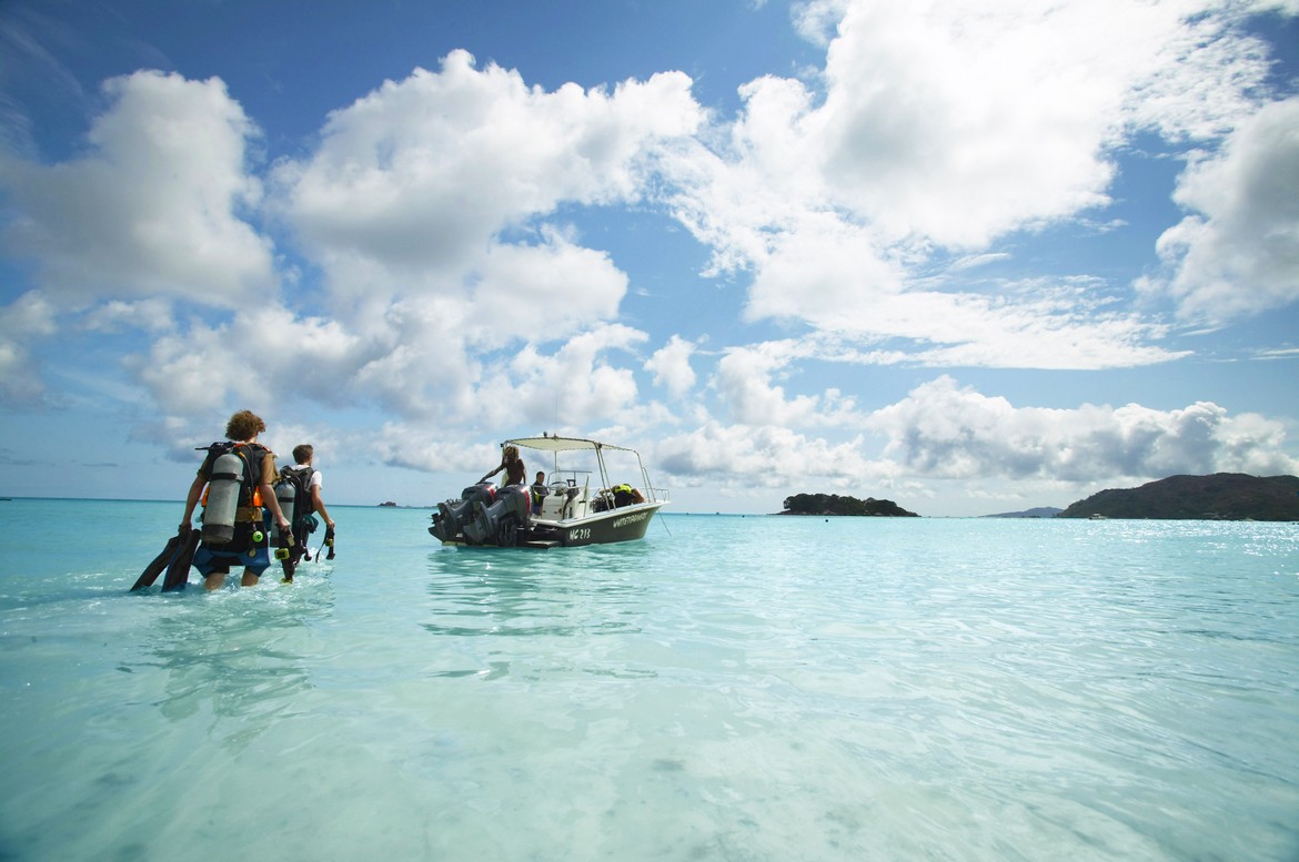Guests walking towards a boat in clear waters at Paradise Sun