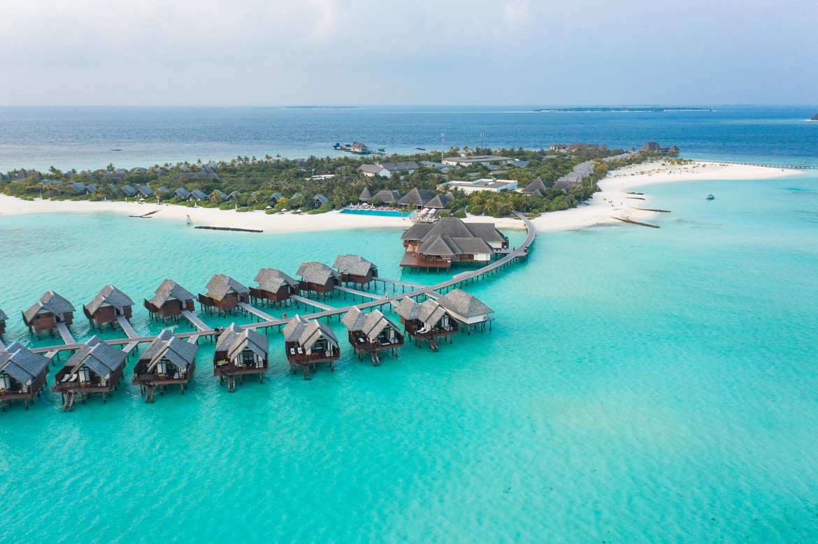 Heritance Aarah overwater villas extending into turquoise waters connected by a wooden walkway