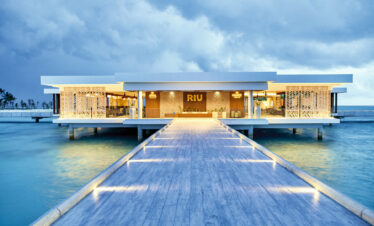 Illuminated walkway leading to the main entrance of Riu Atoll over the water