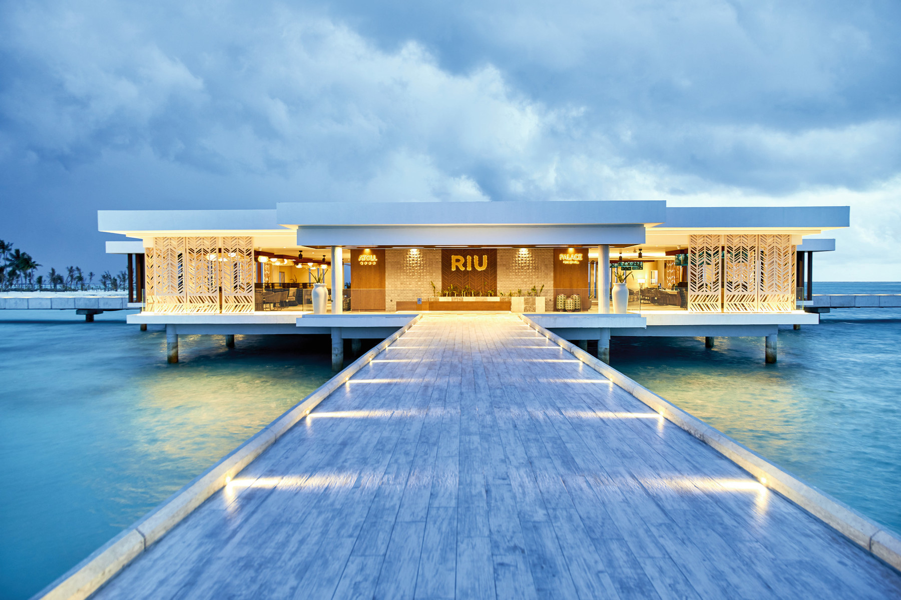 Illuminated walkway leading to the main entrance of Riu Atoll over the water