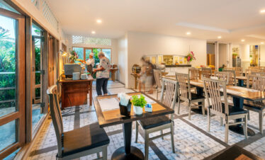 Indoor dining area at Chada Thai Village with wooden tables and chairs and buffet station in the background