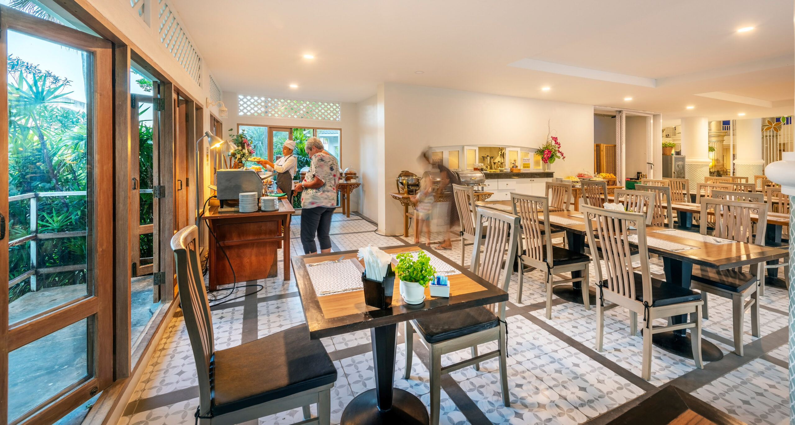 Indoor dining area at Chada Thai Village with wooden tables and chairs and buffet station in the background