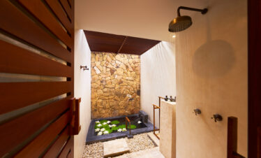 Indoor-outdoor bathroom with rain shower and stone walls at The Tubkaak Krabi