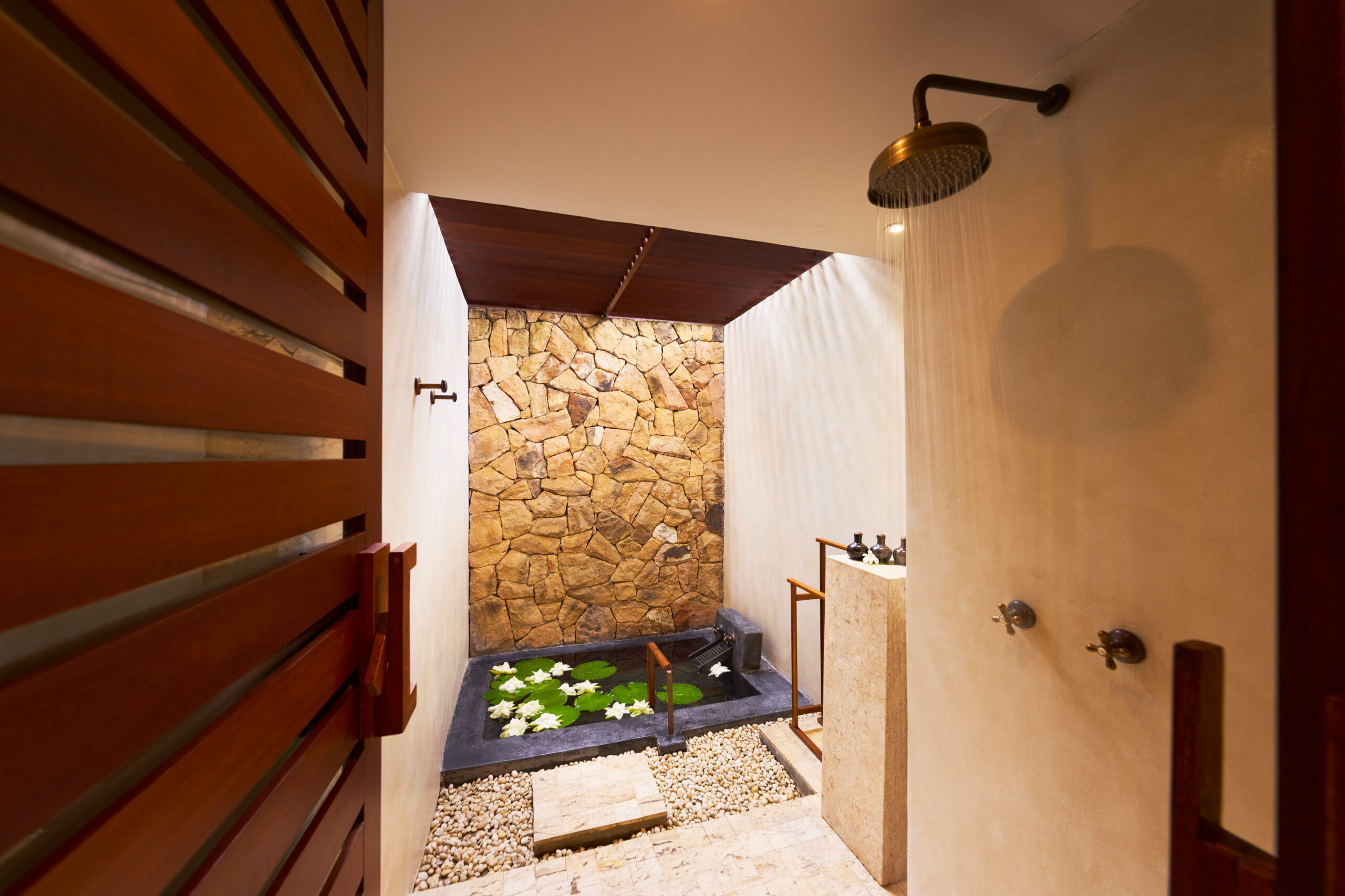 Indoor-outdoor bathroom with rain shower and stone walls at The Tubkaak Krabi
