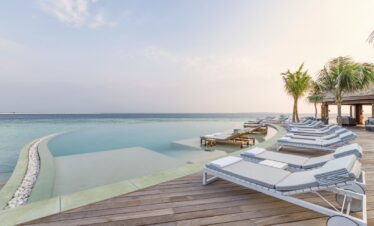 Infinity pool with ocean views and lounge chairs at Hurawalhi Island Resort