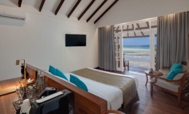 Inside view of a beach villa bedroom opening to the ocean at Adaaran Meedhupparu