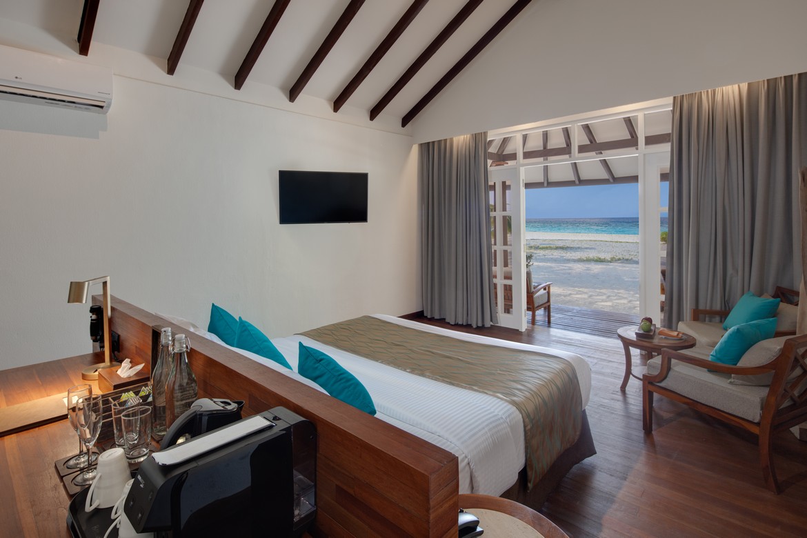 Inside view of a beach villa bedroom opening to the ocean at Adaaran Meedhupparu