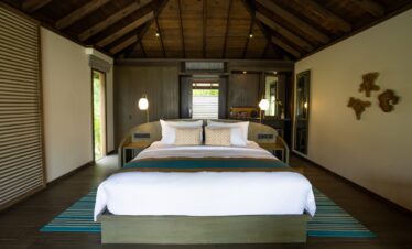 Jawakara Dheru Island beach villa interior with a luxurious bed under a vaulted wooden ceiling