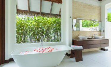 Luxurious bathroom at Heritance Aarah with a freestanding tub and views of tropical greenery
