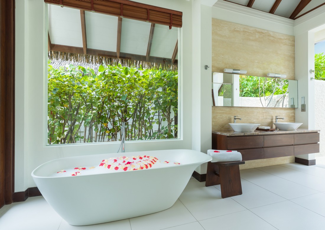 Luxurious bathroom at Heritance Aarah with a freestanding tub and views of tropical greenery