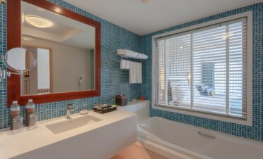 Modern bathroom with a large mirror and blue tiled walls at Diamond Cliff Resort