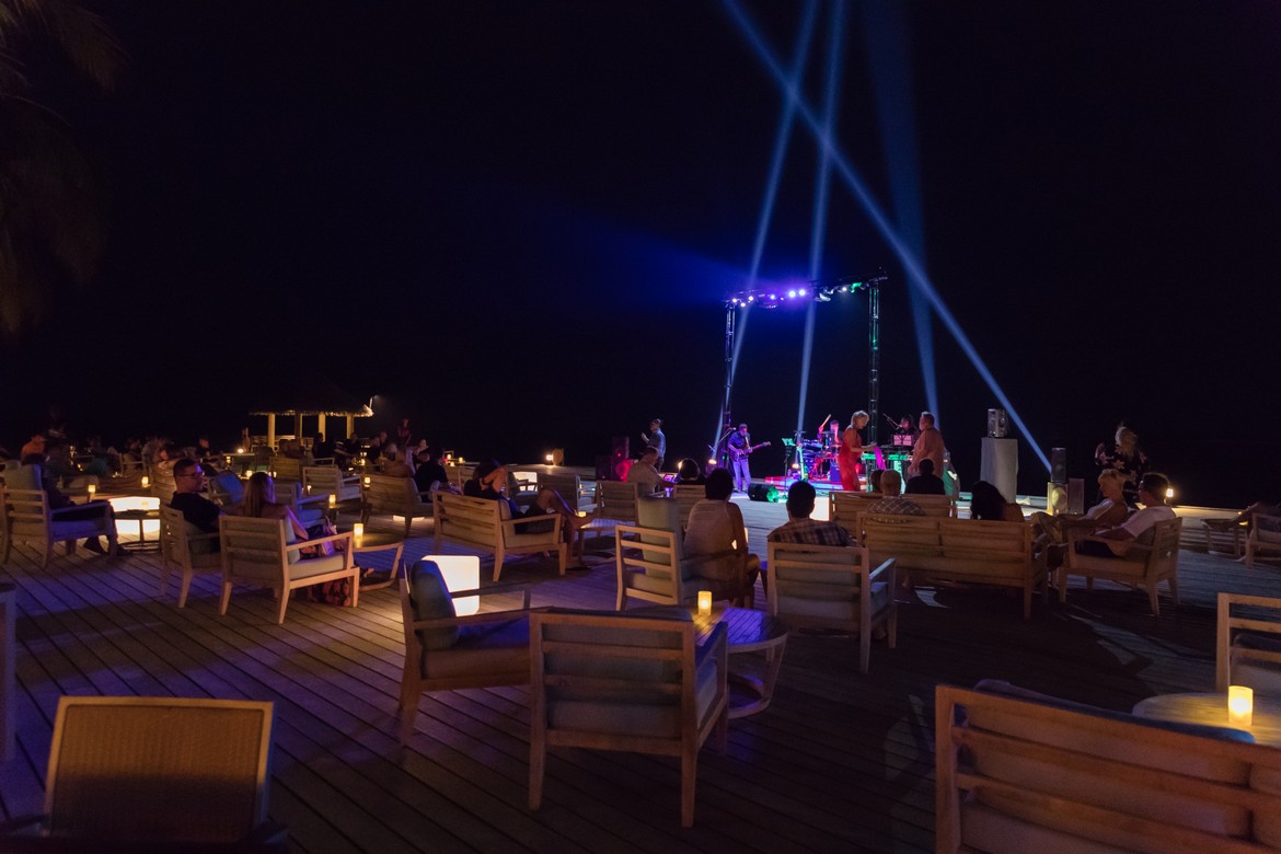 Nighttime entertainment at Vilamendhoo with guests seated under the stars enjoying live music on the deck