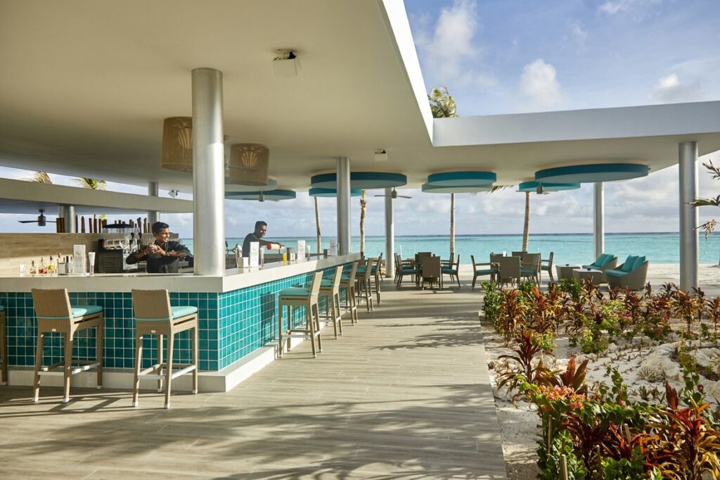 Outdoor bar area with ocean views and seating at Riu Atoll