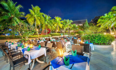 Outdoor dining area at Chada Thai Village with tables set for evening service surrounded by palm trees