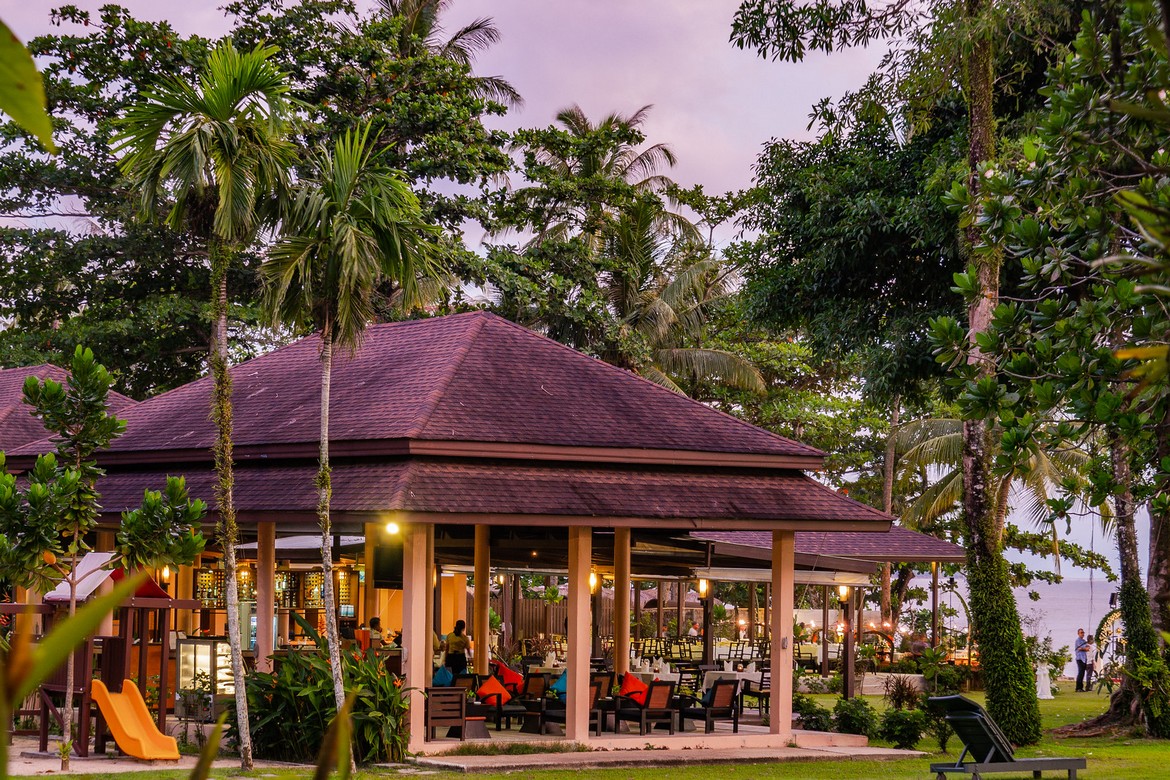 Outdoor dining area at Khao Lak Merlin with palm trees and garden view