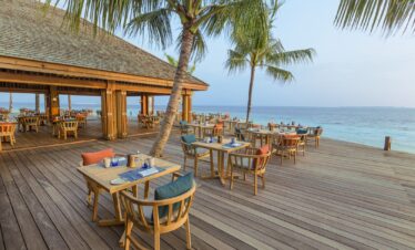 Outdoor dining area by the ocean at Hurawalhi Island Resort