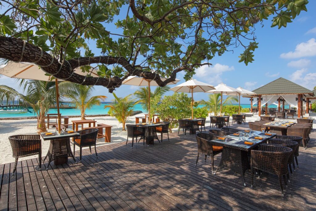 Outdoor restaurant seating area near the beach at Adaaran Meedhupparu