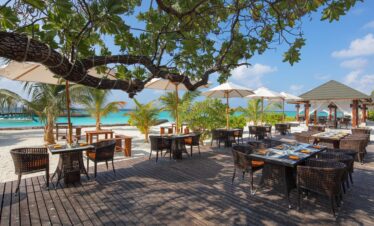 Outdoor restaurant seating area near the beach at Adaaran Meedhupparu