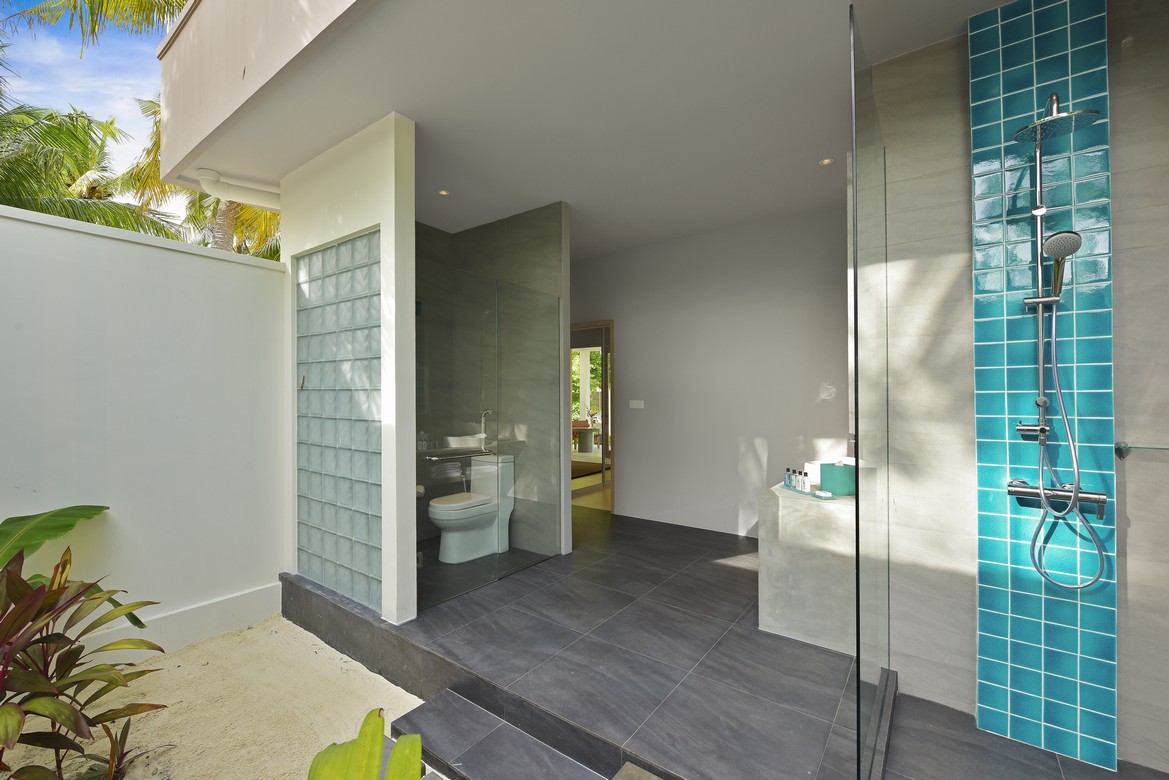 Outdoor shower area with teal tiles at Dhigali villa