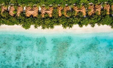 Overhead shot of beachfront villas at Ayada Maldives nestled among palm trees along the shoreline