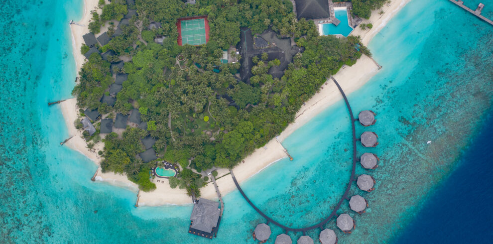 Overwater villas and island view at Adaaran Meedhupparu surrounded by clear blue water