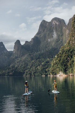 Paddleboarders enjoying peaceful lake views near mountains at 500Rai Floating Resort