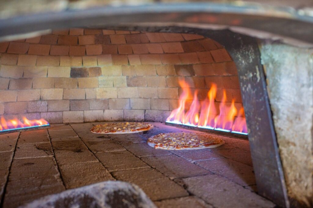 Pizzas cooking in a traditional wood-fired oven at Paradise Sun