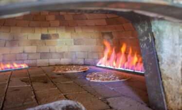 Pizzas cooking in a traditional wood-fired oven at Paradise Sun