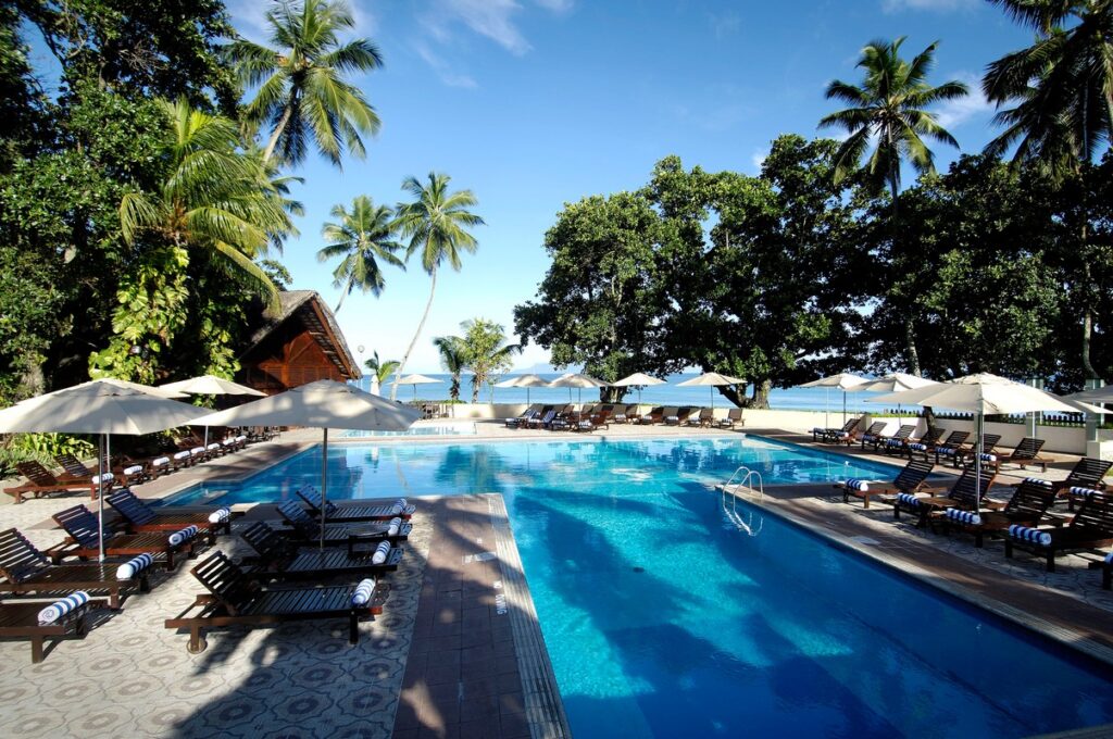 Pool area with sun loungers and palm trees at Berjaya Beau Vallon