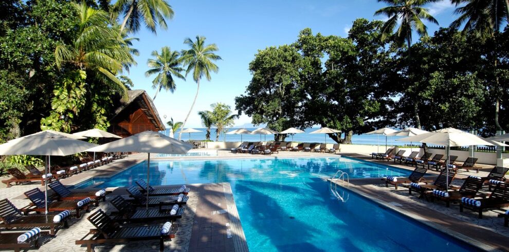 Pool area with sun loungers and palm trees at Berjaya Beau Vallon