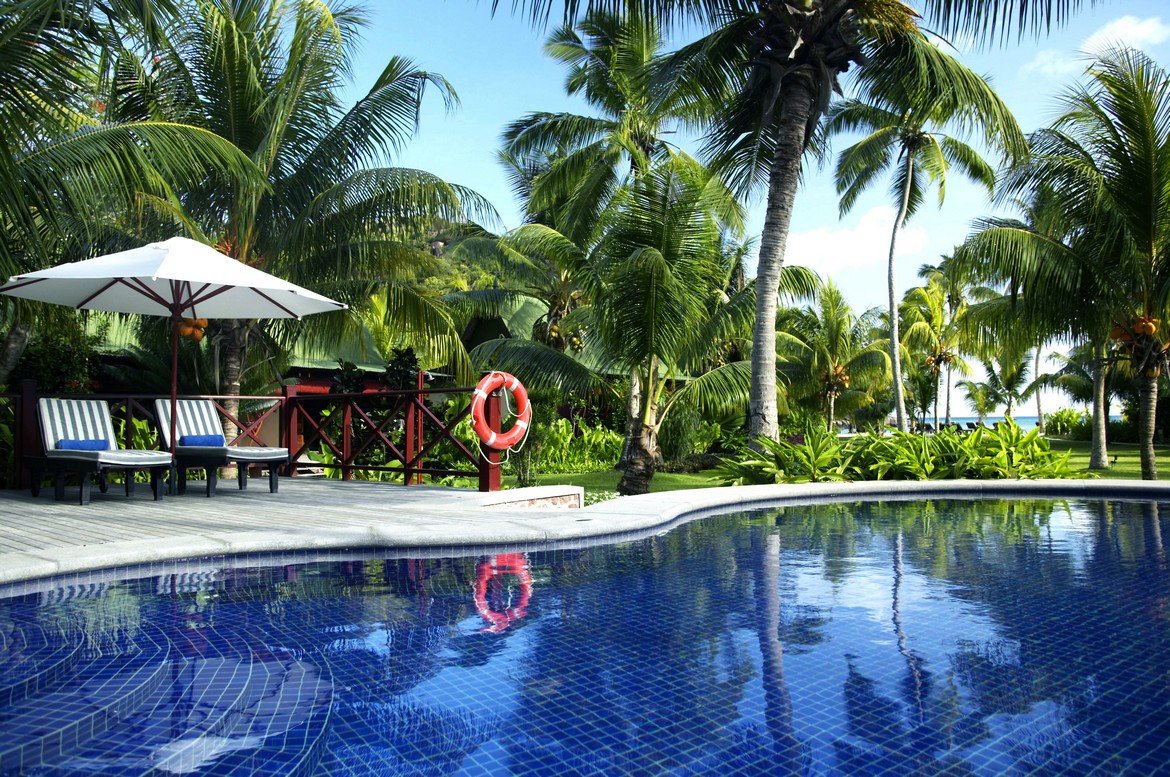Pool with reflections of palm trees and sun loungers at Paradise Sun