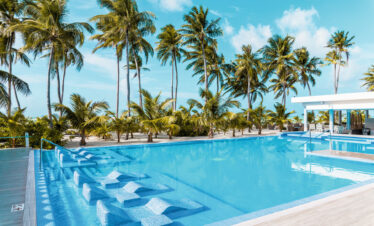 Poolside area with palm trees and loungers at Riu Palace