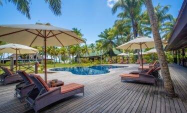 Pool with reflections of palm trees and sun loungers at Paradise Sun
