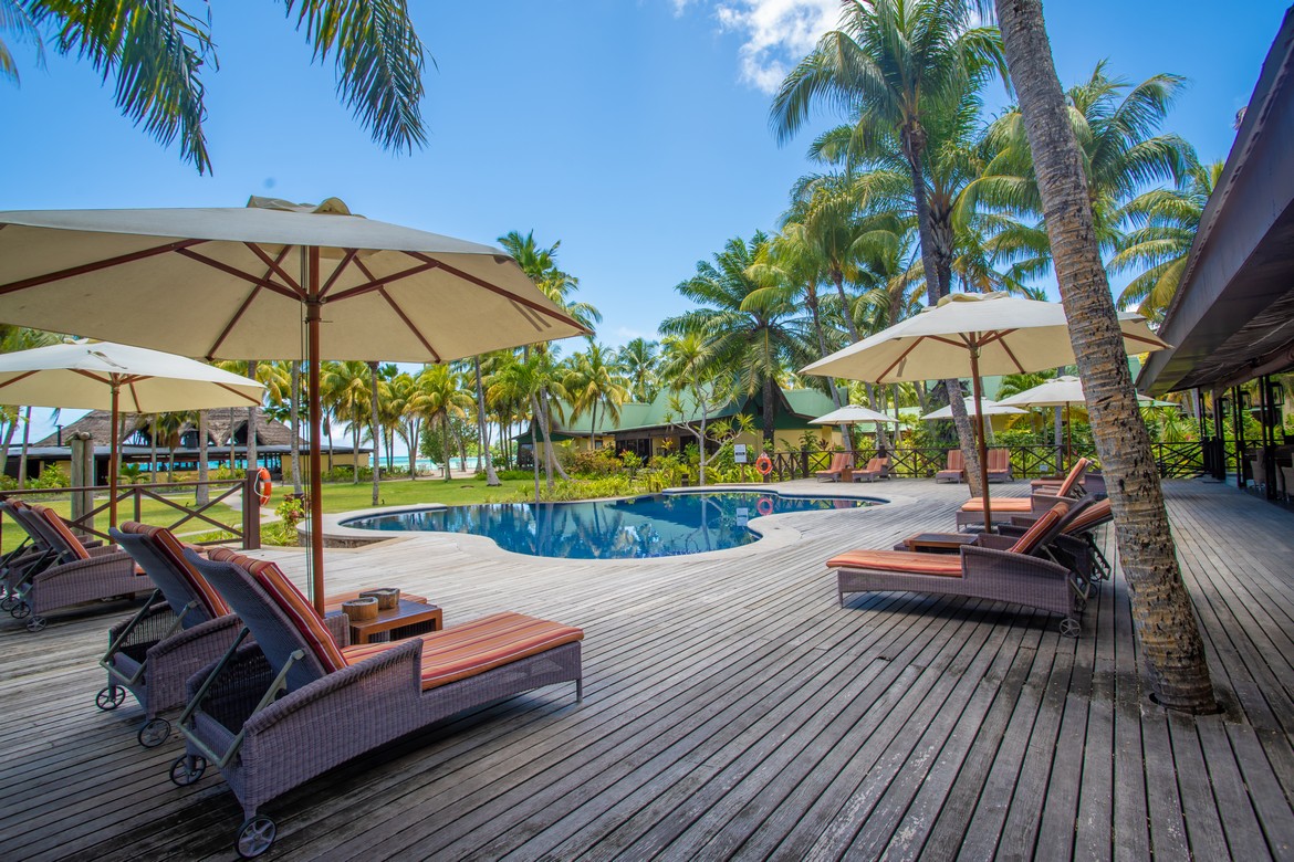 Pool with reflections of palm trees and sun loungers at Paradise Sun