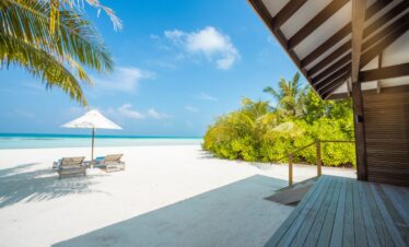 Pristine white sandy beach at Jawakara Dheru Island with sun loungers and palm trees