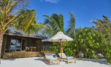 Secluded beach at Jawakara Dheru Island with sun loungers and lush greenery