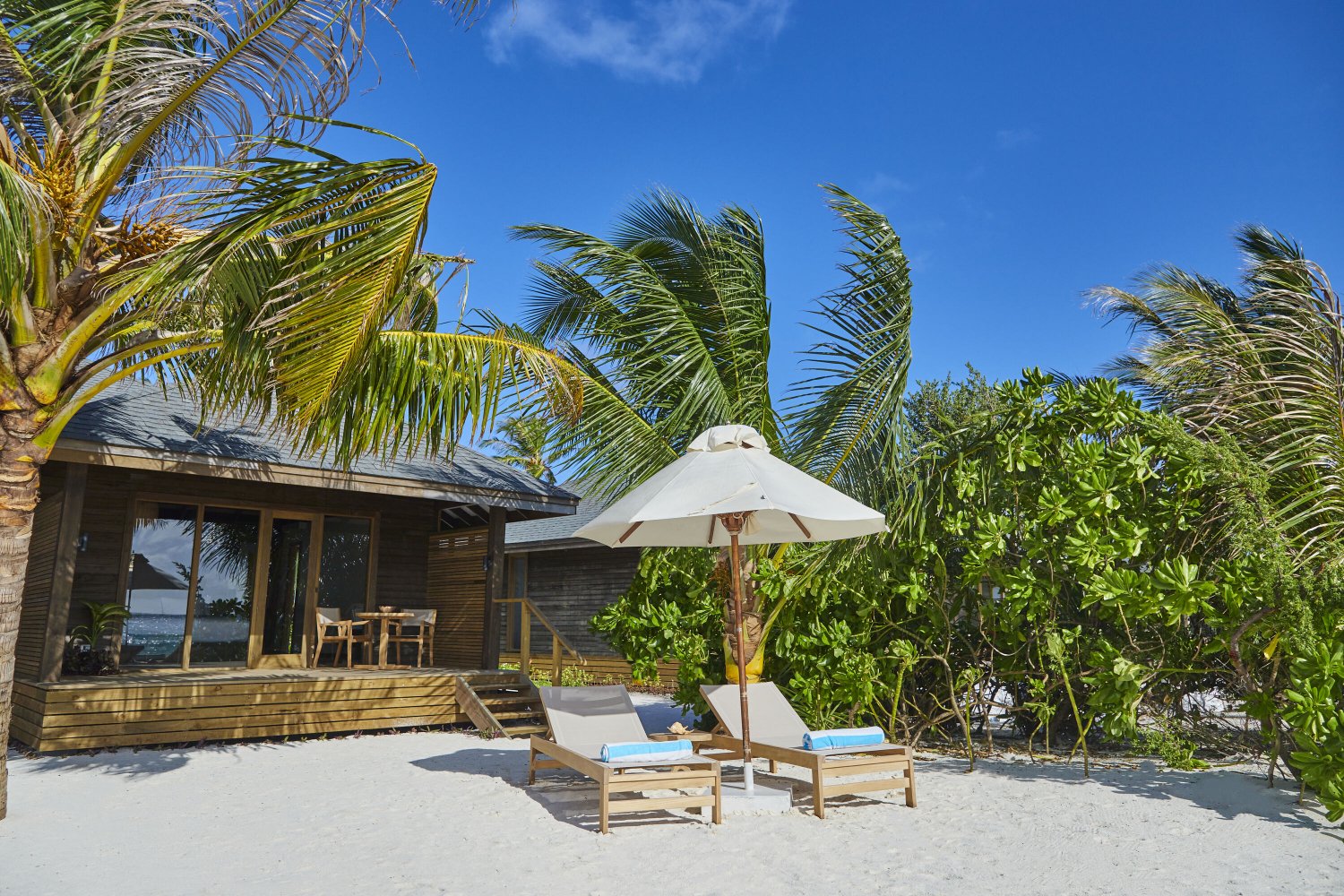 Secluded beach at Jawakara Dheru Island with sun loungers and lush greenery