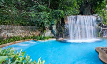 Serene waterfall flowing into a pool surrounded by lush greenery at Diamond Cliff Resort