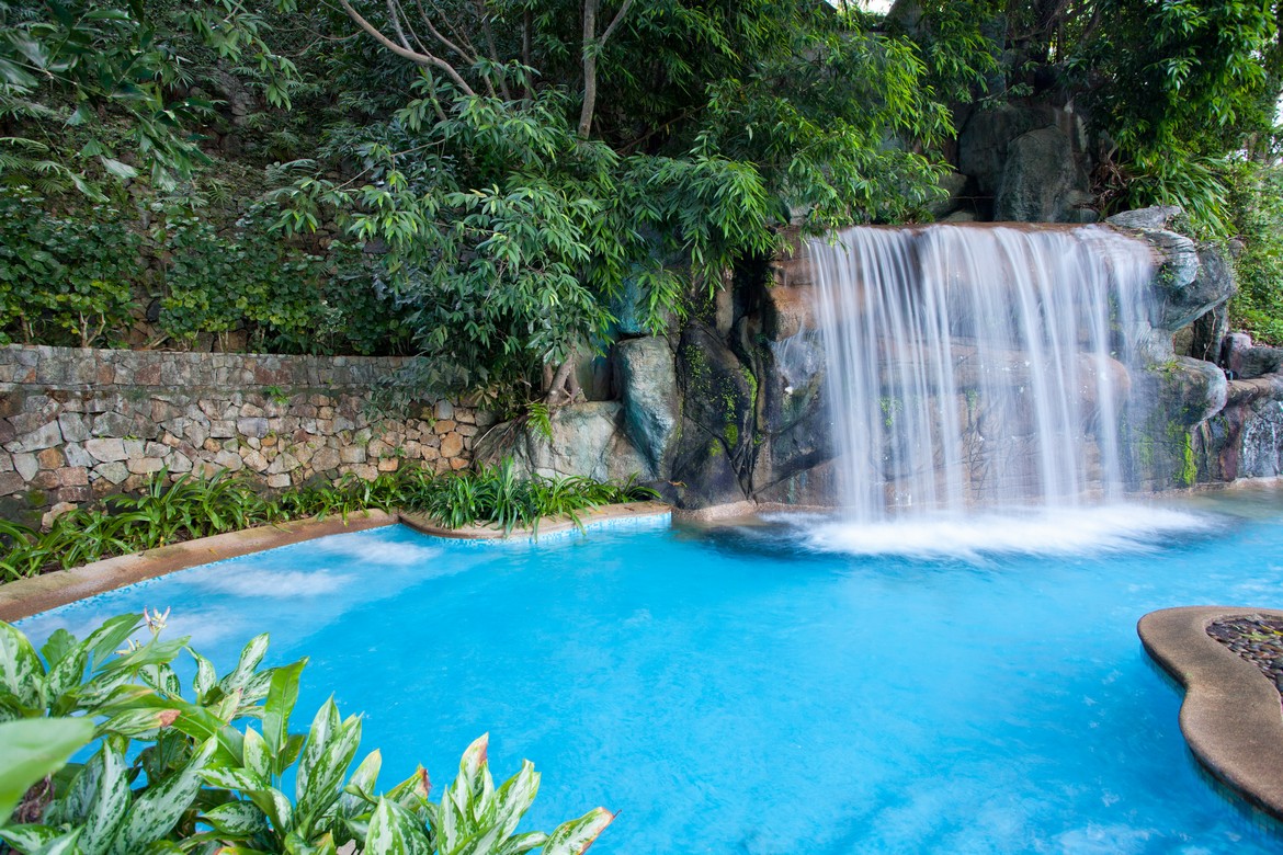 Serene waterfall flowing into a pool surrounded by lush greenery at Diamond Cliff Resort