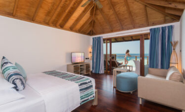 Spacious bedroom at Vilamendhoo with wooden ceiling opening onto a private deck with ocean views