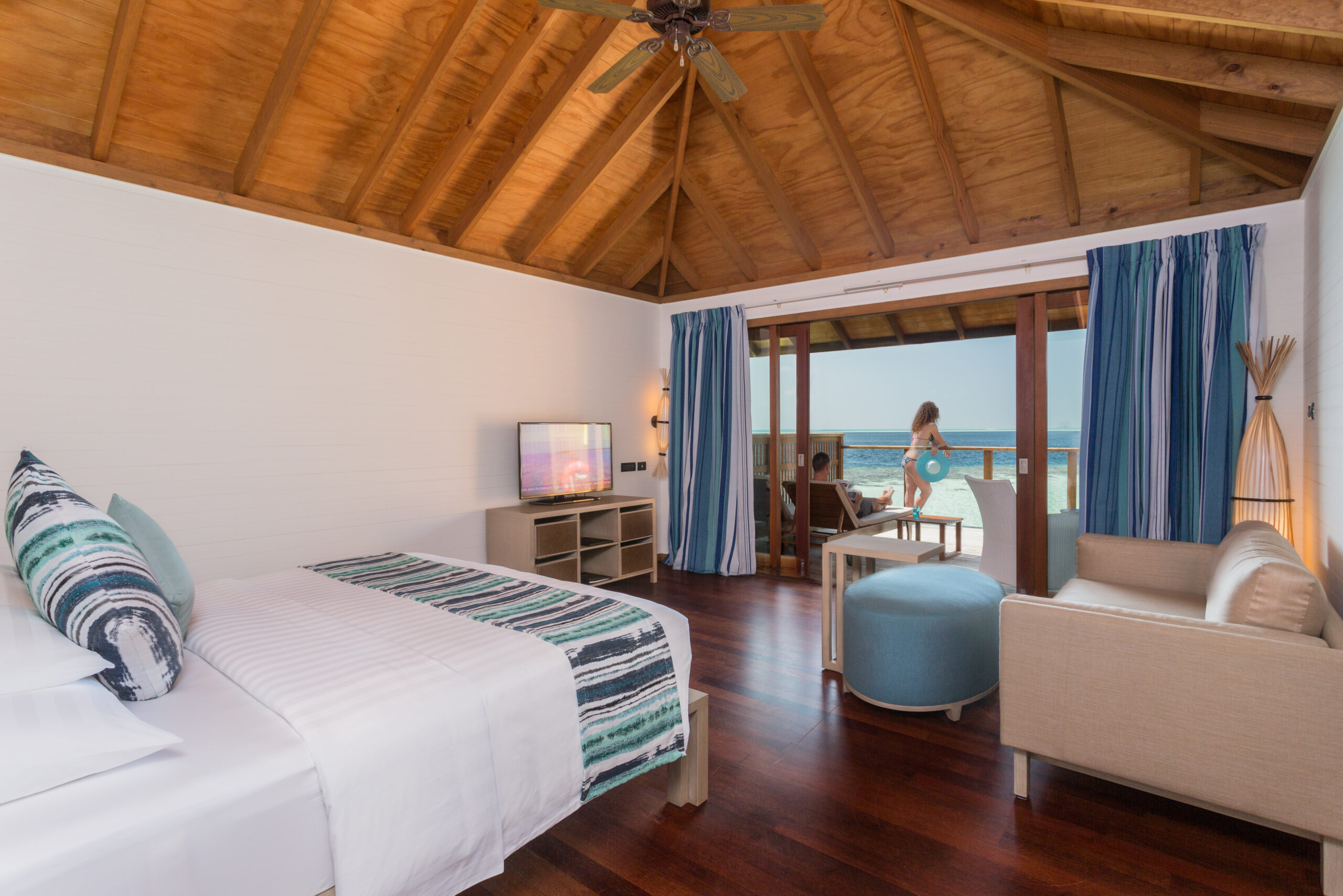 Spacious bedroom at Vilamendhoo with wooden ceiling opening onto a private deck with ocean views