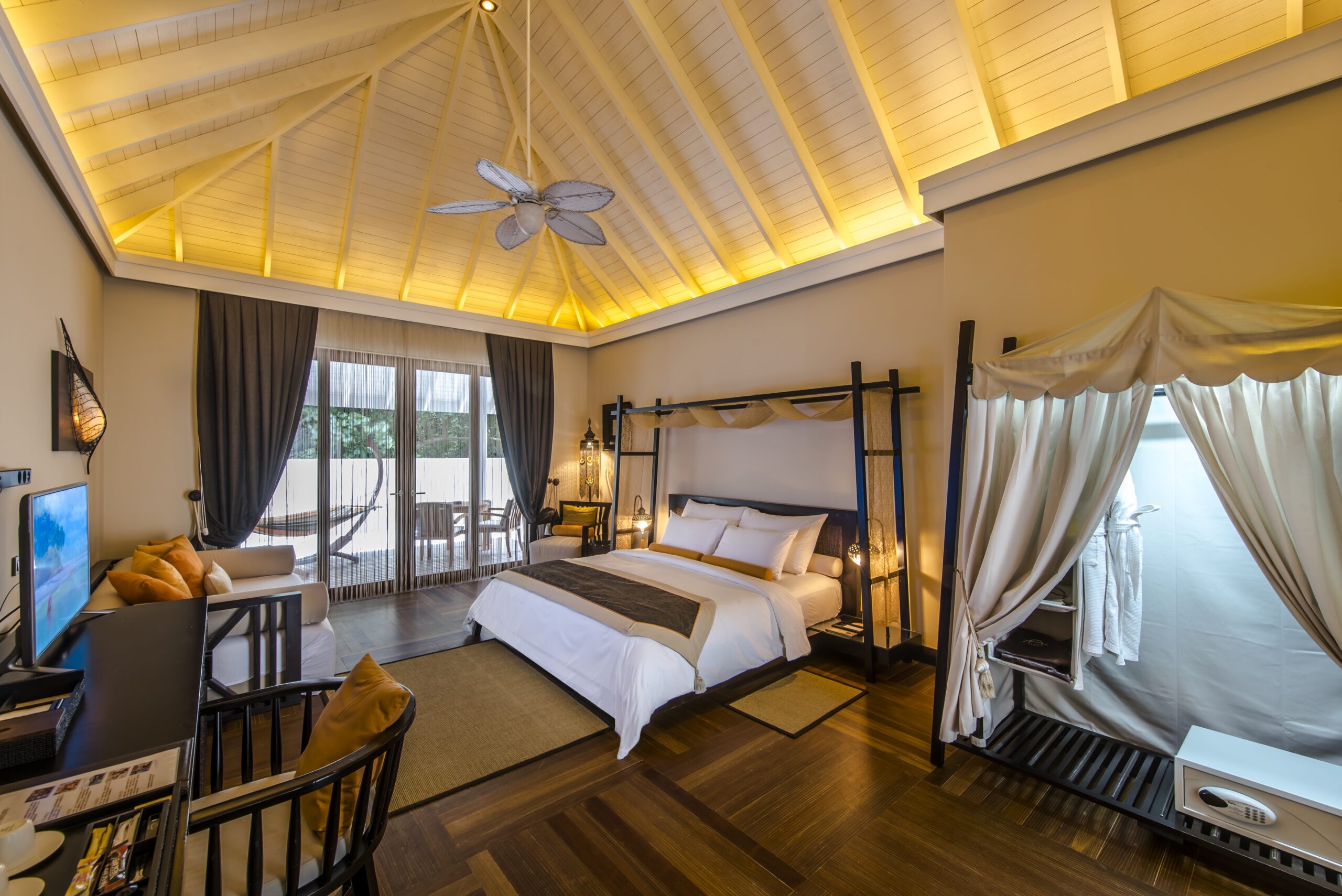 Spacious bedroom suite at Ayada Maldives featuring high ceilings and warm lighting