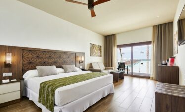 Spacious bedroom with king bed and ocean view at Riu Atoll