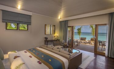 Spacious bedroom with ocean view and direct deck access at Hurawalhi Island Resort