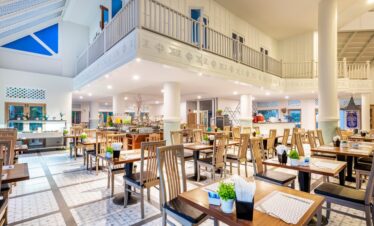 Spacious dining hall at Chada Thai Village with wooden furniture and elegant decor under high ceilings