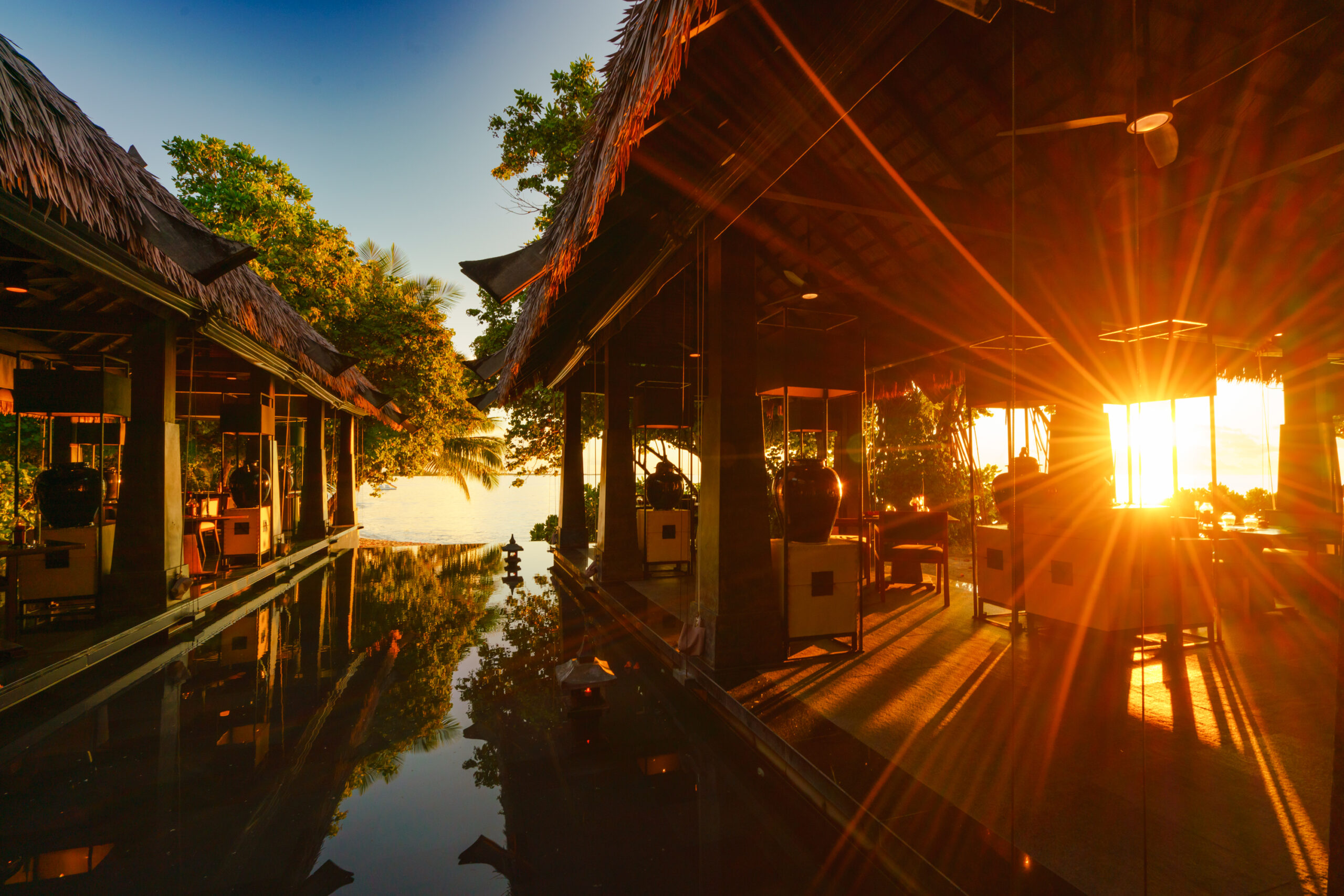 Sun setting over serene reflection pool at Ayada Maldives surrounded by tropical foliage