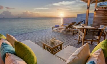 Sunset view from a deck with seating at Hurawalhi Island Resort