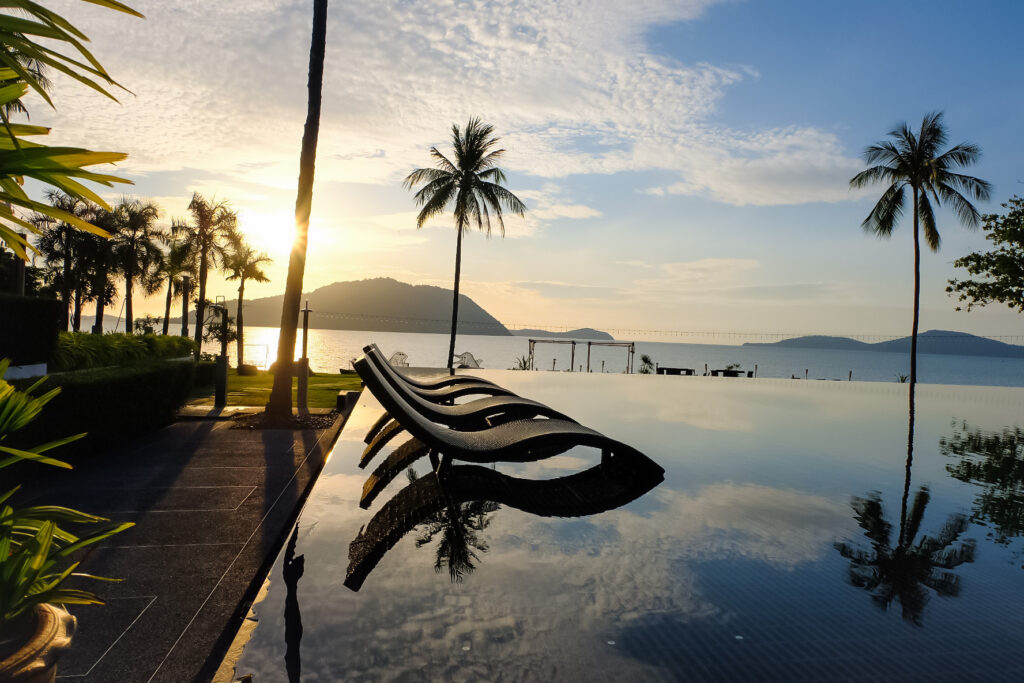Sunset view from the infinity pool at The Vijitt Resort with palm trees and calm waters