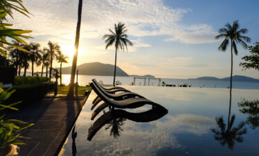 Sunset view from the infinity pool at The Vijitt Resort with palm trees and calm waters